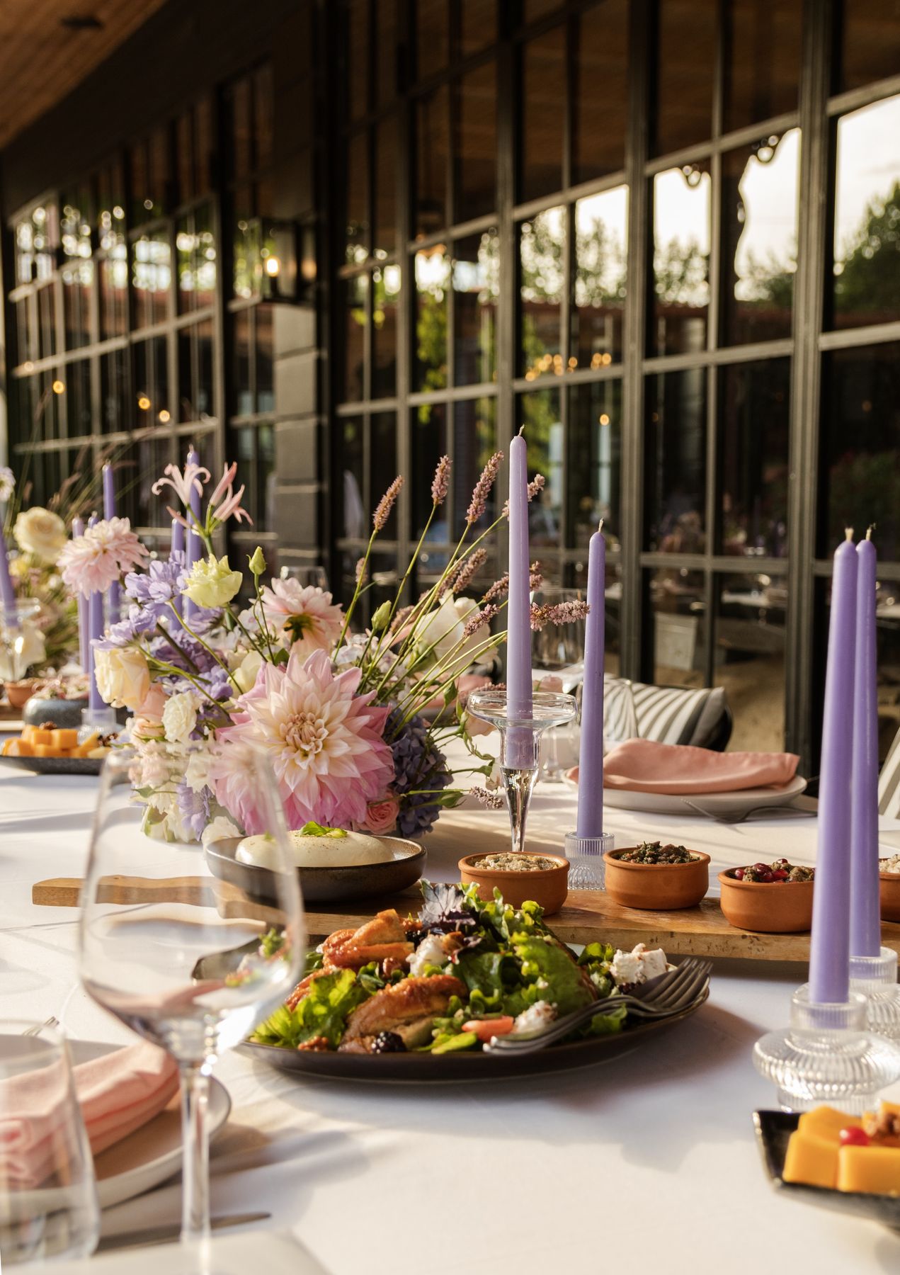 Restaurant table styled with lavender candles and seasonal flowers