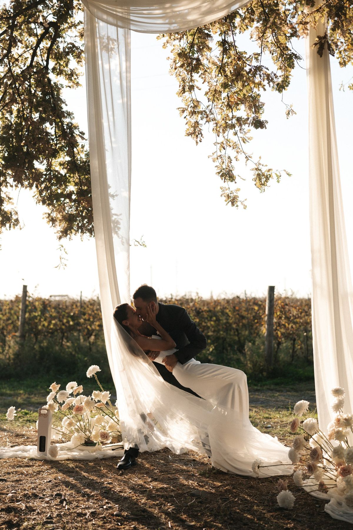 Newlyweds beneath a silk arch with ivory flowers