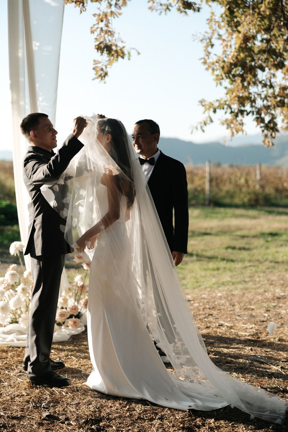 Bride and groom under a silk arch in a vineyard